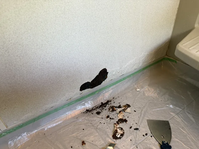 施工前：浴室壁の下部が腐食し破損した状態