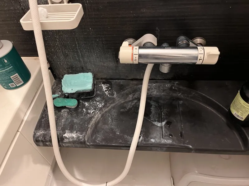 施工前：石鹸カスと水垢が残る浴室のカウンターと水栓